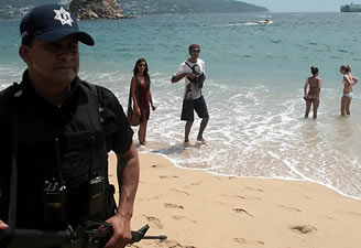 Tourists enjoy the beach near a police officer on patrol in Acapulco. The U.S. State Department issued a warning for Acapulco, its first for a popular tourist resort, after a year of violence in the city.